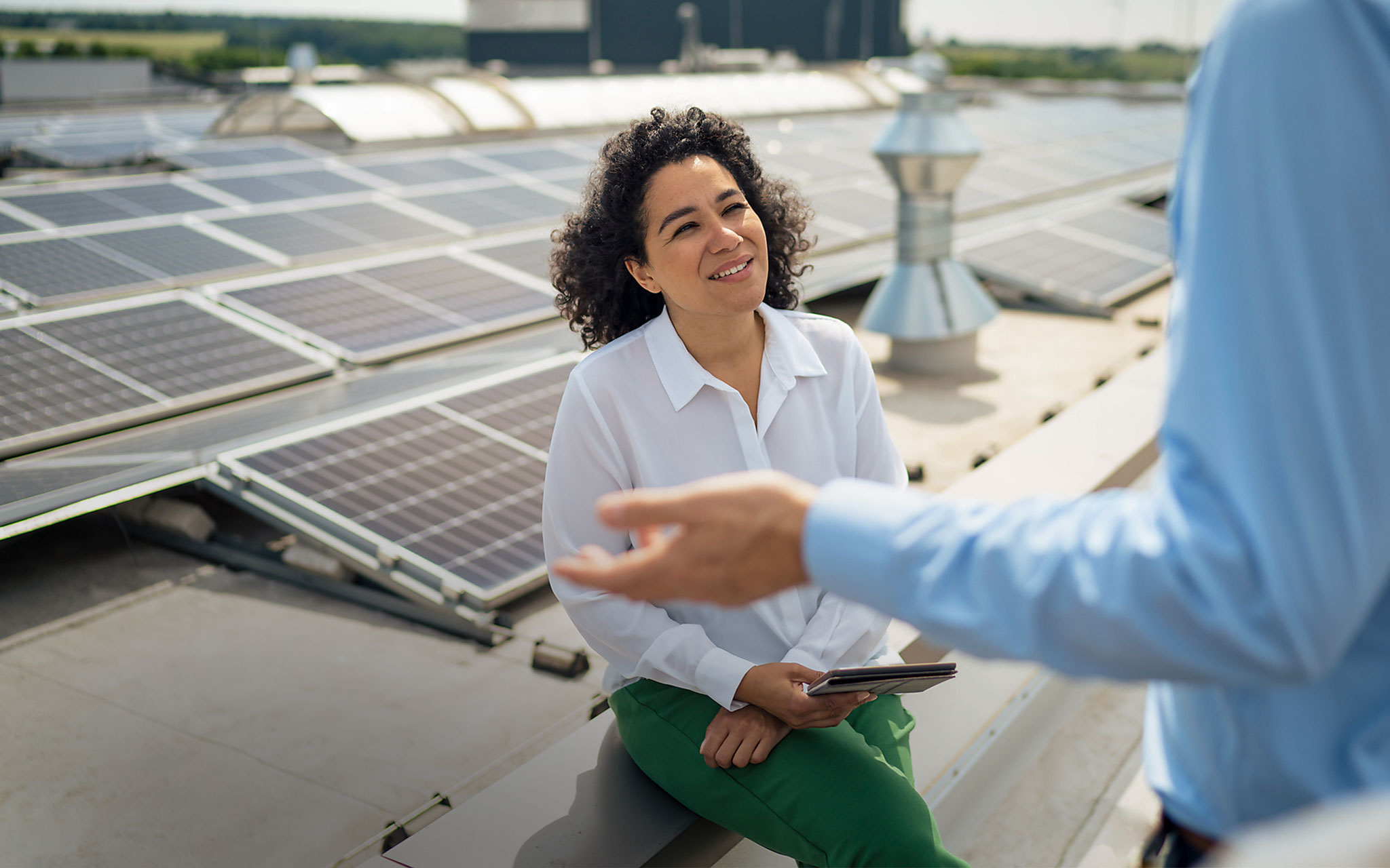 Eine Frau und ein Mann unterhalten sich, Photovoltaikanlage im Hintergrund