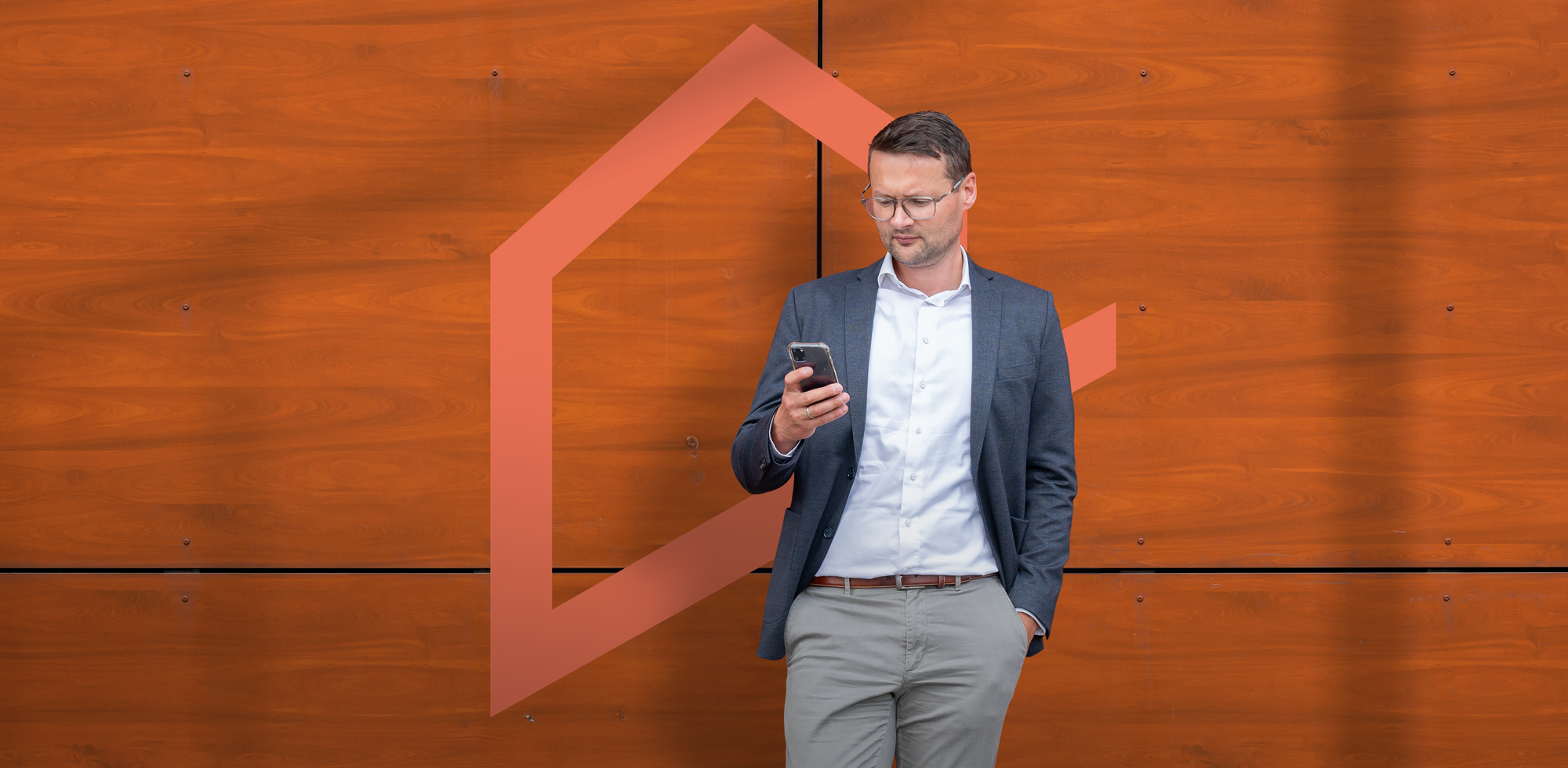 Geschäftsmann mit Smartphone in der Hand vor einer Wand