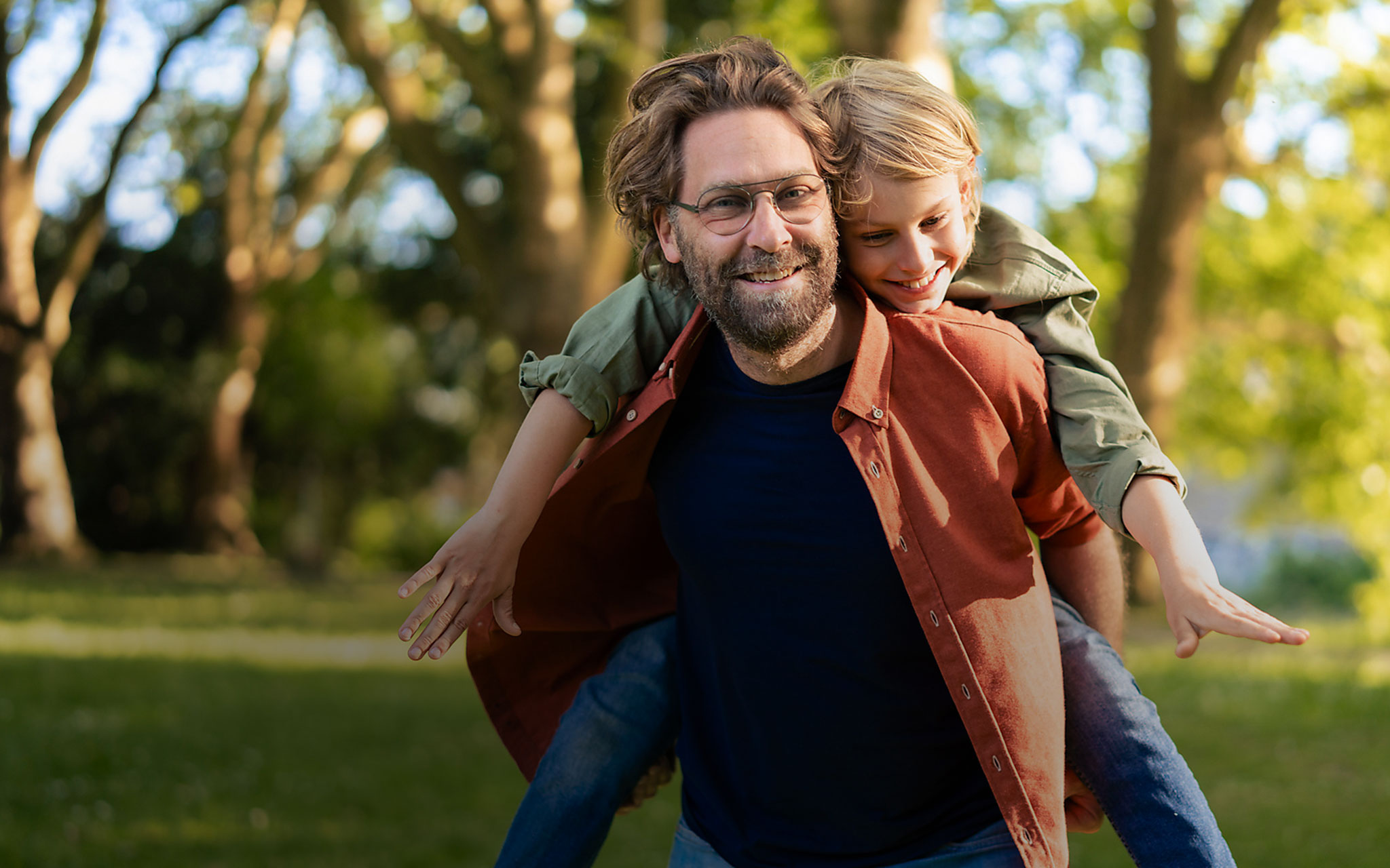 Glücklicher Vater, der seinen Sohn im Park huckepack nimmt