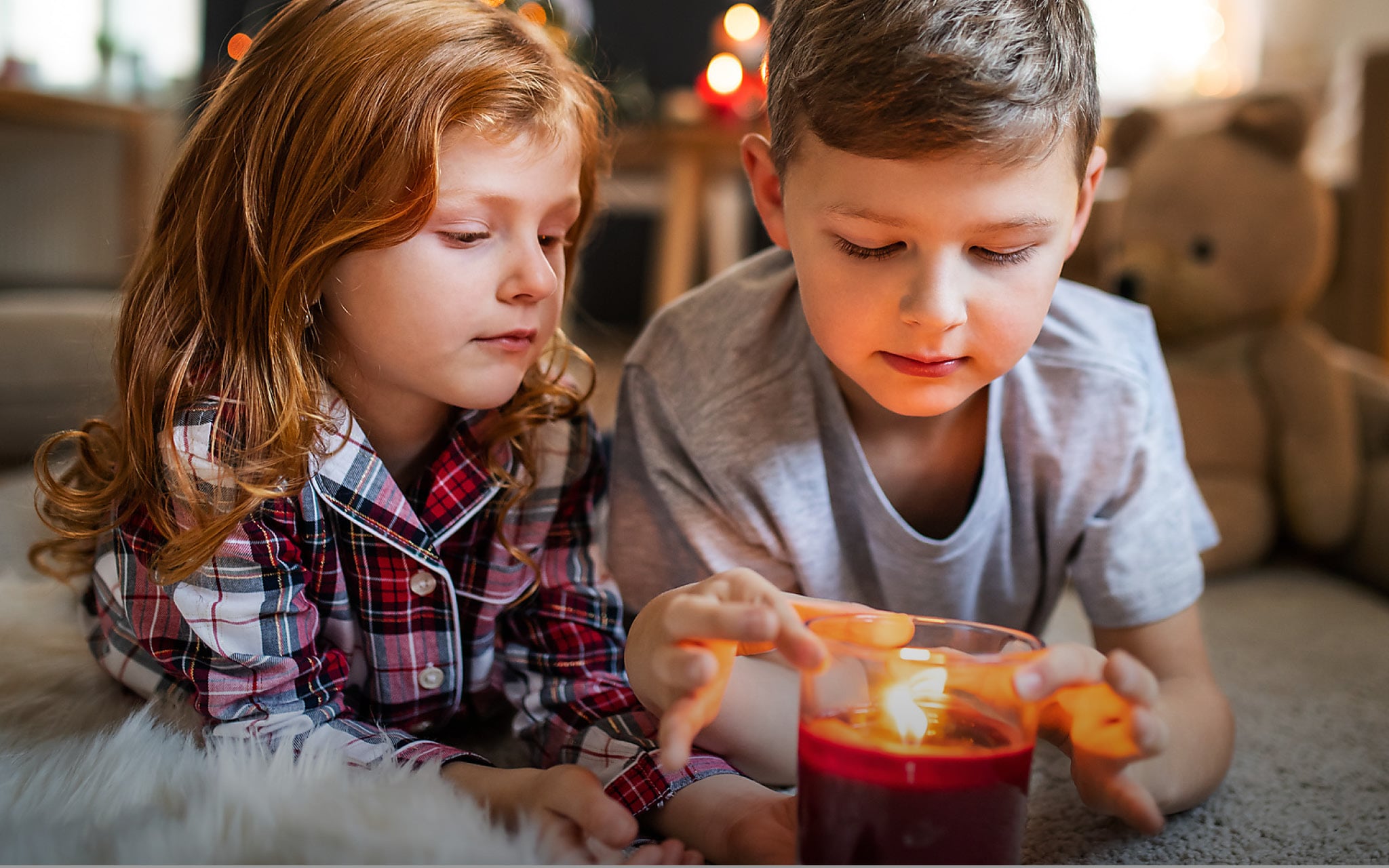 Kinder spielen mit einer brennenden Kerze