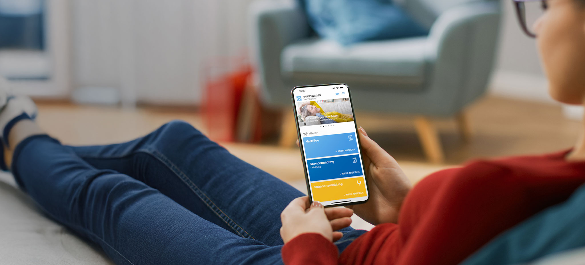Eine Frau auf dem Sofa mit Smartphone in der Hand, die sich die Mein VWI App anschaut anschaut