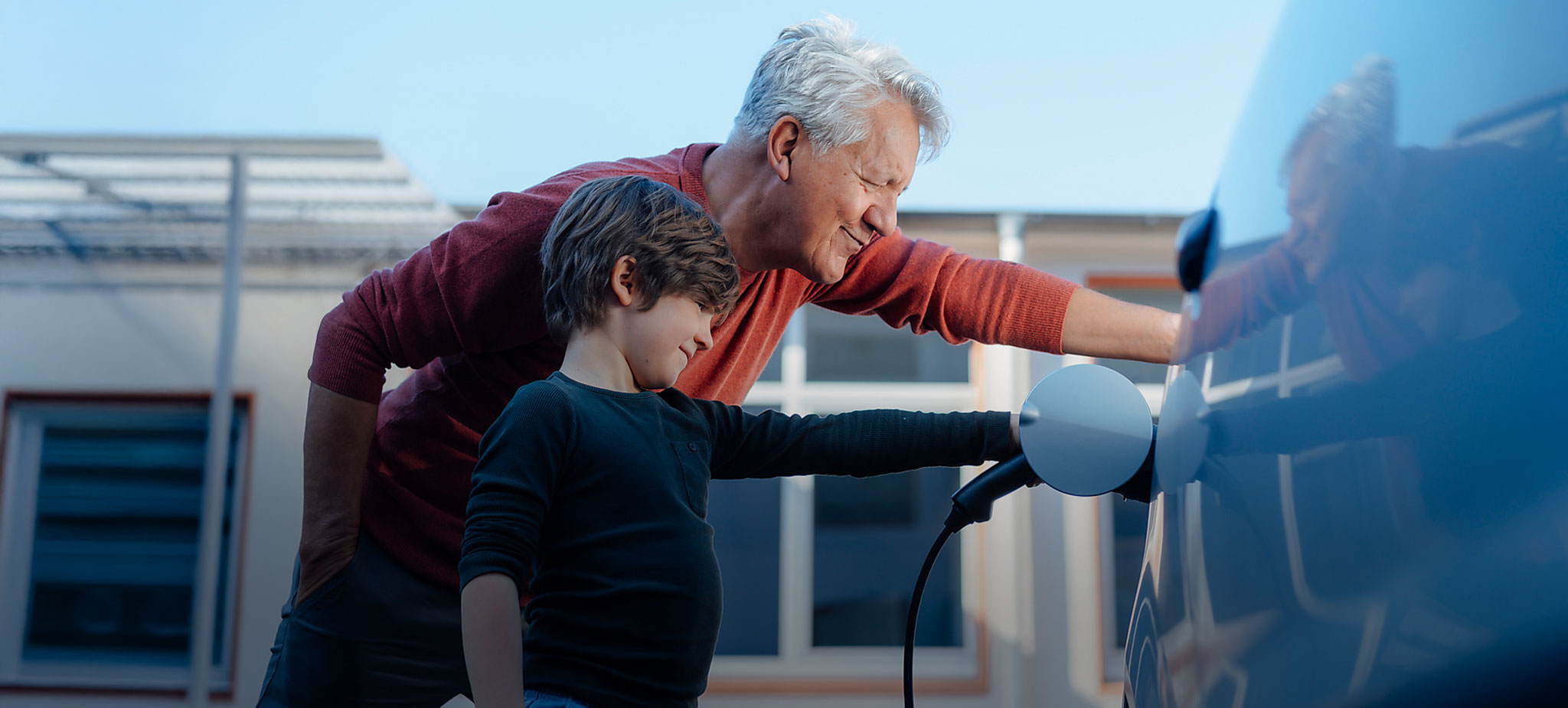 Grossvater und Enkel laden Elektroauto