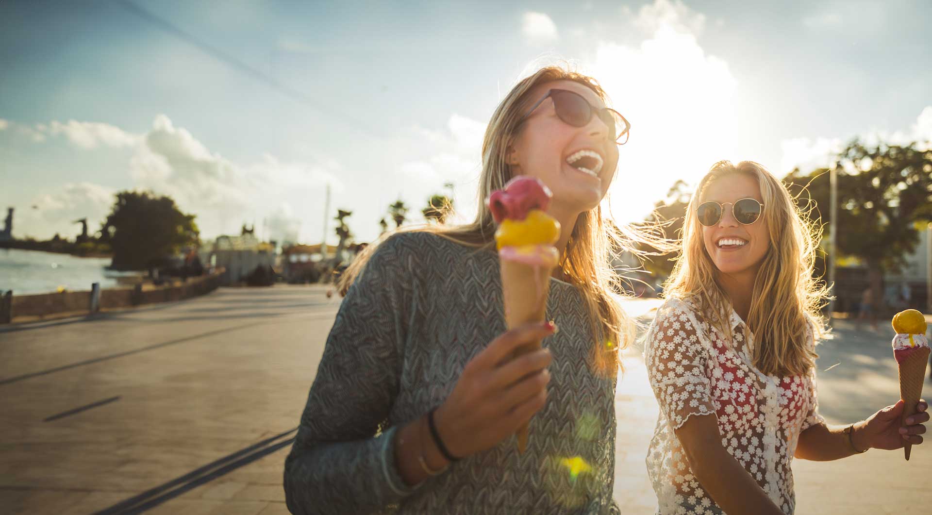Zwei Frauen essen lachend Eis in der Sonne