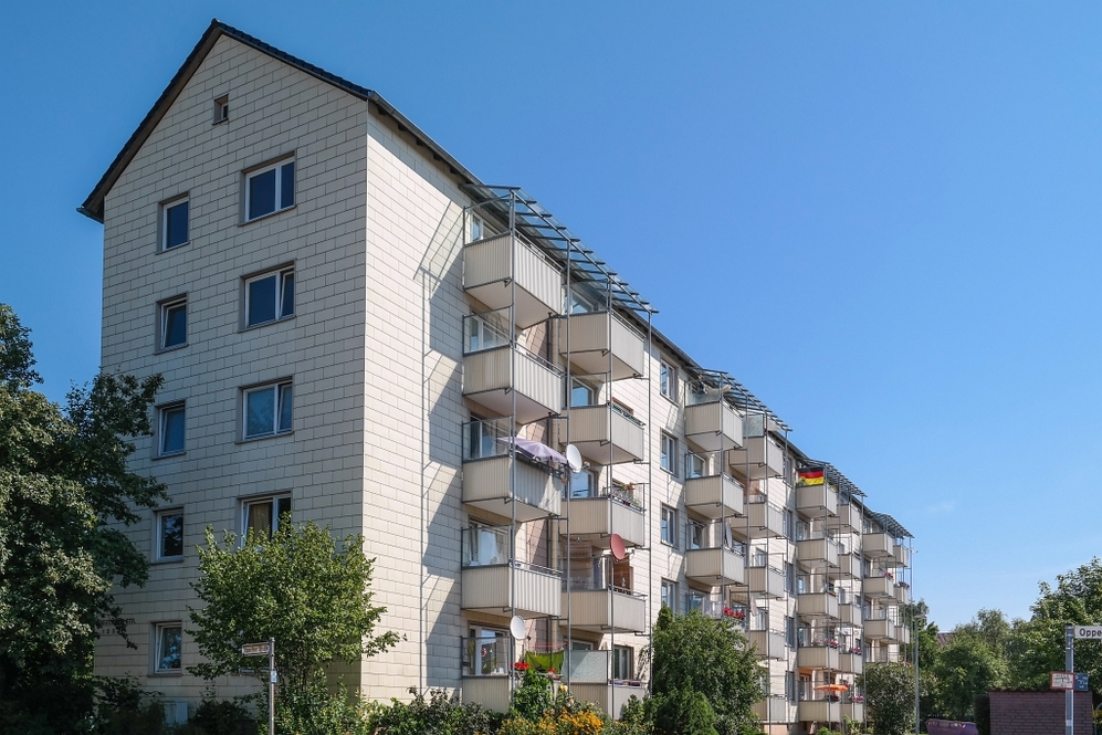 Mehrstöckiges Wohngebäude mit Balkonen unter klarem blauem Himmel.